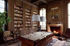 a pool table in the middle of a living room with lots of bookshelves