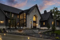 a large house that is lit up at night with lights on the windows and steps leading to it