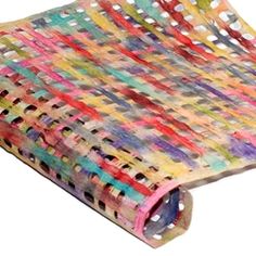 a multicolored blanket is folded on top of a white surface with holes in it