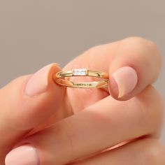 a woman's hand holding a yellow gold ring