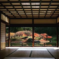 an open room with sliding glass doors leading to a garden and trees in the background