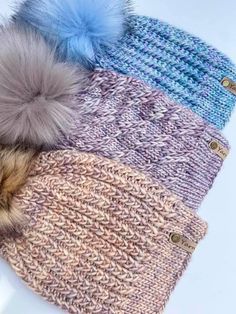 four different colored knitted hats with pom - poms on top of each other