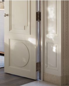 an open door with a circular handle on the front and side panels in white painted wood