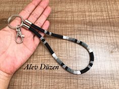 a hand is holding a black and white leash with silver metal clasps on it