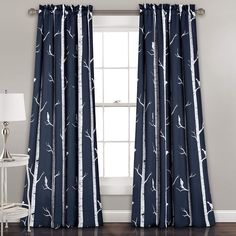 the curtains in this room are blue with white trees on them and one window is closed