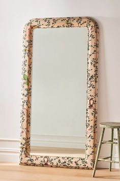 a mirror sitting on top of a wooden floor next to a stool