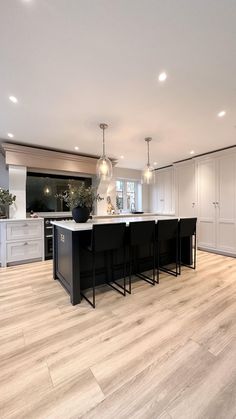 a large kitchen with an island in the middle and white cabinets on both sides is shown