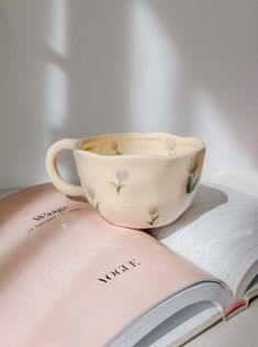 an open book with a cup on top of it