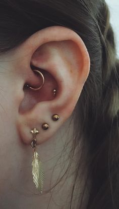 a woman wearing gold ear piercings with an arrow