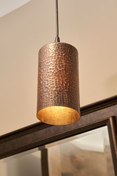 a light fixture hanging from the ceiling in a living room with a mirror behind it