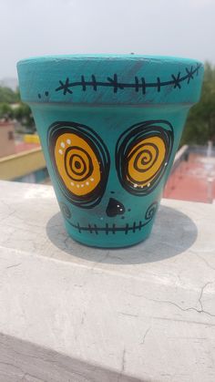 a blue planter with an image of a skull painted on it