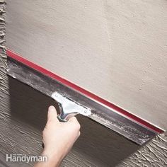 a person is using a paint roller on a wall with a red strip in front of it