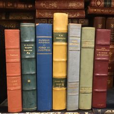 a row of books sitting on top of a book shelf next to each other in front of a pile of books