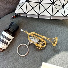 a trumpet shaped keychain sitting on top of a couch next to a bottle of alcohol