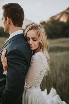 a bride and groom embracing in a field