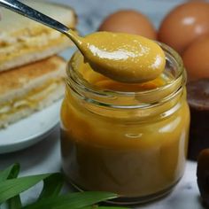 a spoon full of peanut butter next to some eggs and other food on a table