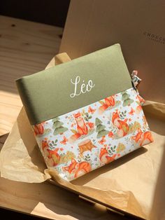 an orange flowered pouch sitting on top of a piece of paper next to a box