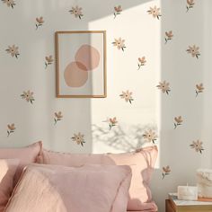 a bed with pink sheets and pillows next to a framed painting on the wall above it