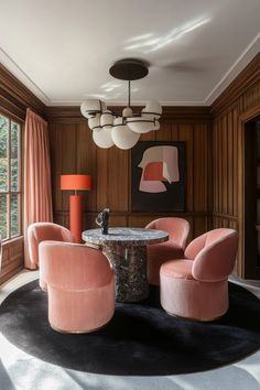 a living room with pink chairs and a round table