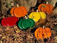 several orange and green frisbees sitting on the ground next to a tree