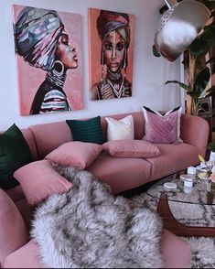 a living room filled with pink couches and paintings on the wall next to a coffee table