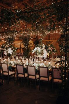 a long table with white flowers and greenery is set up for a formal dinner