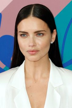 a woman with long black hair wearing a white suit