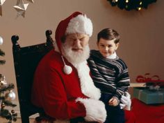 a little boy sitting next to santa claus