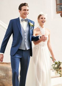 a bride and groom are walking down the stairs in their wedding attire, smiling at each other