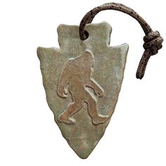 a silver ornament with a bigfoot on it's side hanging from a cord