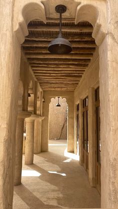 an empty hallway with columns and a ceiling light hanging from it's side wall