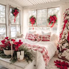 a bedroom decorated for christmas with red and white decorations on the windowsill, plaid bedspread, poinsettis and candles