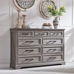 a dresser with drawers and two mirrors on the wall