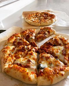 two pizzas sitting on top of a white counter next to each other in front of a window