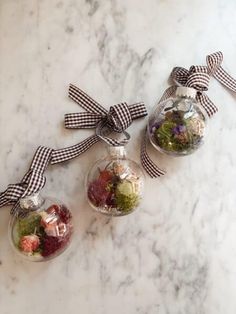 three glass ornaments with bows on them sitting on a marble counter top next to each other