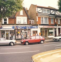 cars are parked on the side of the road in front of shops and businesses,