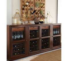 a wooden cabinet with wine glasses and bottles on it in front of a wall mounted art piece