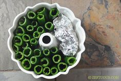 a white bowl filled with green peppers covered in foil