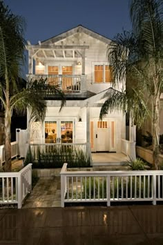 a large white house with palm trees in the front yard