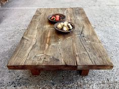 a wooden table with two bowls of fruit on it and one bowl of strawberries