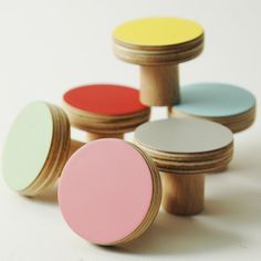 four round wooden knobs with colored tops on white surface, one is yellow and the other is pink