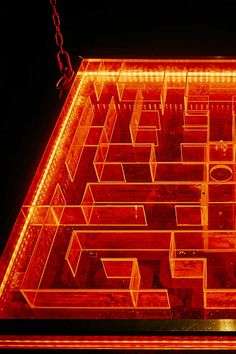 an illuminated maze in the shape of a house is shown at night with red lights