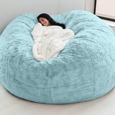 a woman laying in a large blue bean bag chair