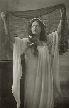 an old black and white photo of a woman dressed in ancient greek clothing holding a veil over her head