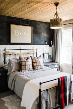 a bedroom with black walls and white bedding has plaid pillows on the headboard