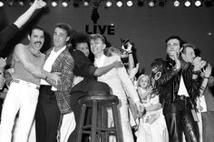 a group of people standing around each other in front of a stage with their arms up