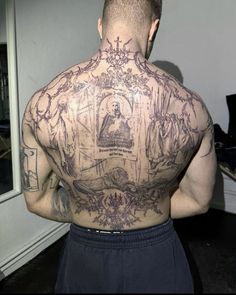 the back of a man with tattoos on his upper and lower body, standing in front of a mirror