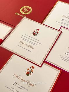 the wedding stationery is red and gold, with floral designs on each card sleeve