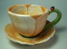 a ceramic tea cup and saucer with a ladybug on it