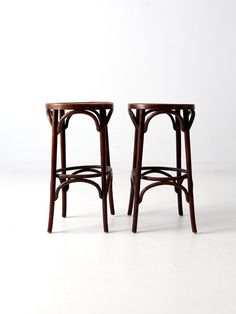 two wooden stools sitting next to each other on a white floor with no one around them